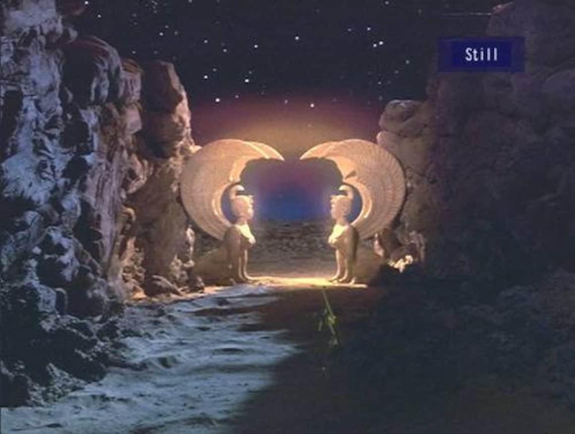 Screenshot of the Sphinx Gate from Neverending Story; Two sphinx statues facing each other at the end of a rocky pass