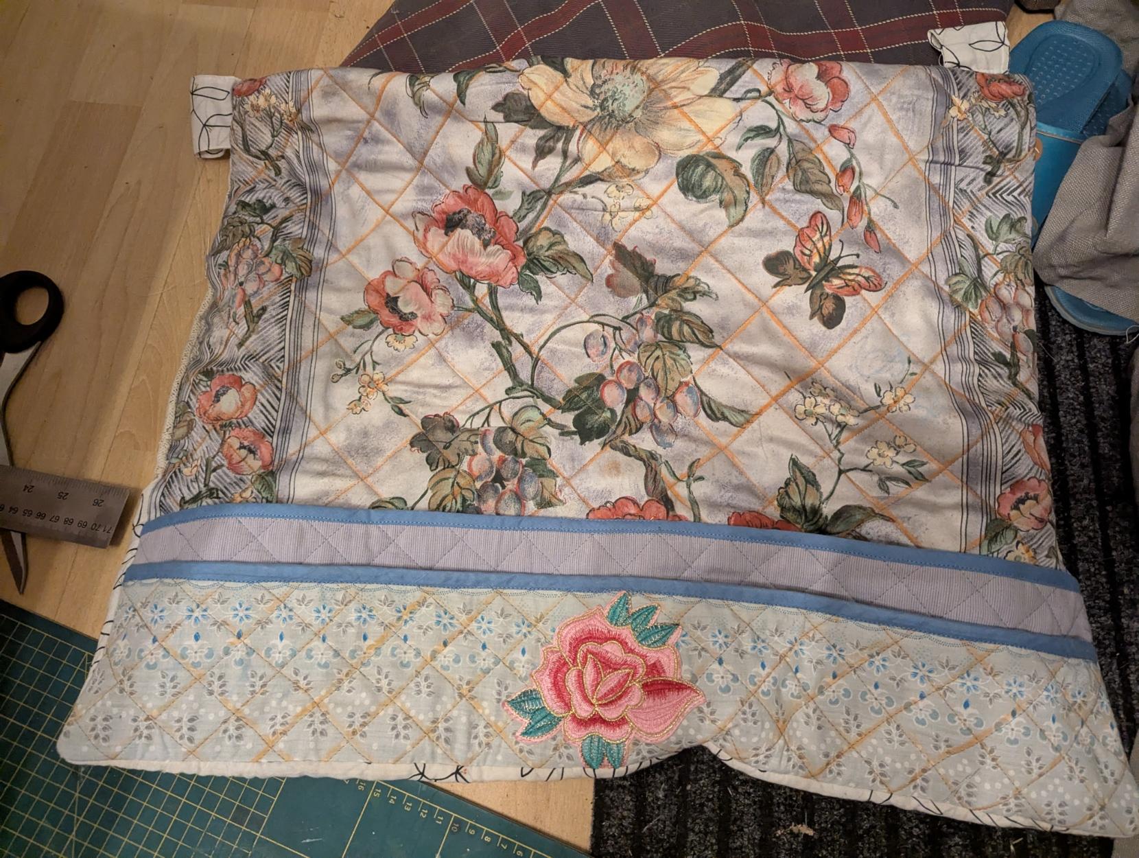 The mat with pockets flat on the floor, with on thread catchers attached yet. A pink rose patch is featured front center.