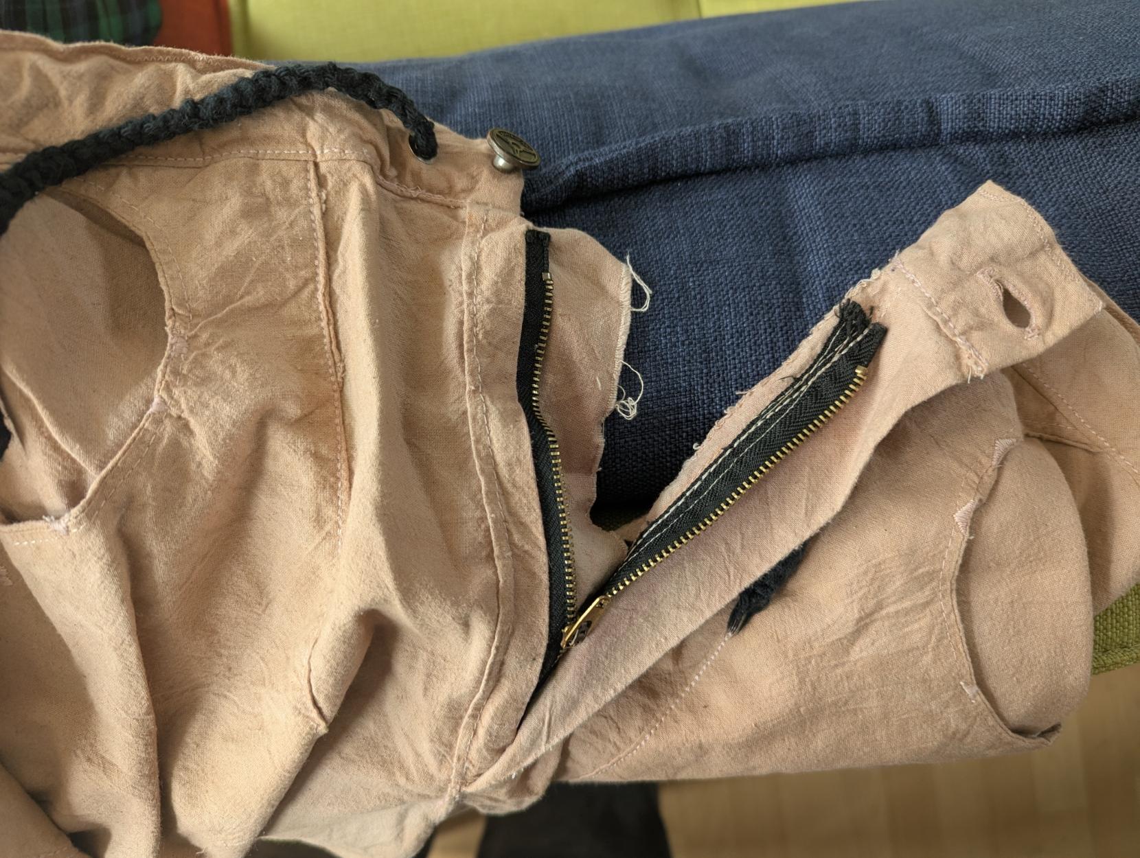 A close up of the fly of a pair of pants. The waistband stops too early, though it's invisible when you close the pants