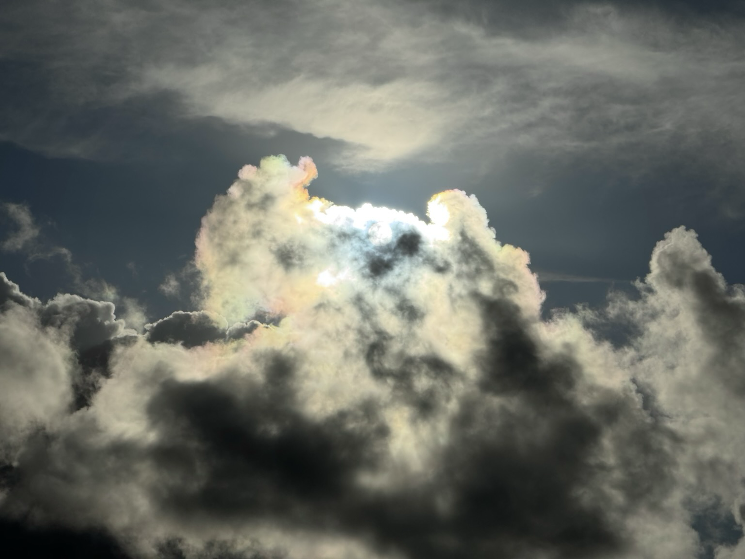 The sun shining through a layer of clouds making the light fracture into rainbow colours.