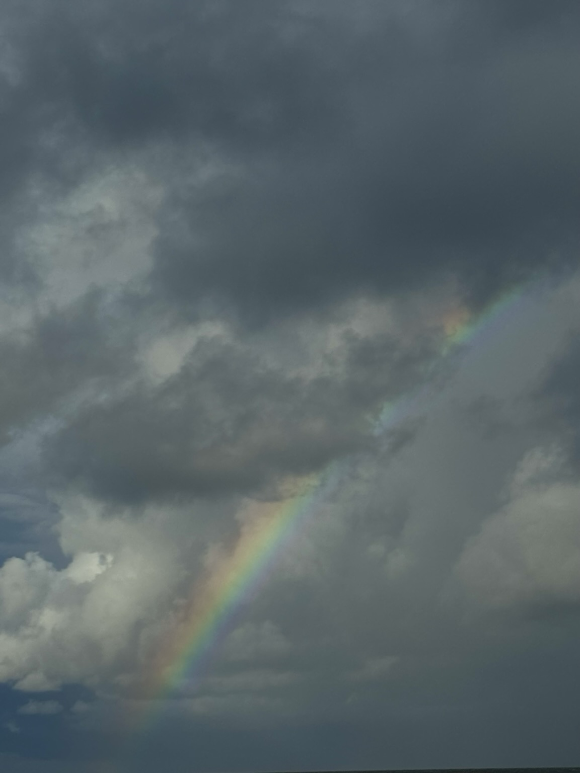 A rainbow bursting through some dark storm clouds.